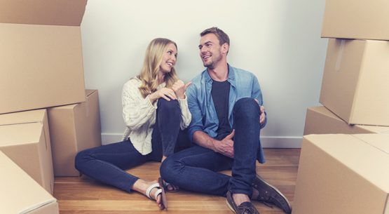 Young couple sitting in new house with packing boxes.